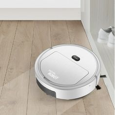 a roomba that is on the floor in front of a white wall and wooden floors