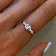 a woman's hand with a diamond ring on top of her finger and an engagement band in the middle