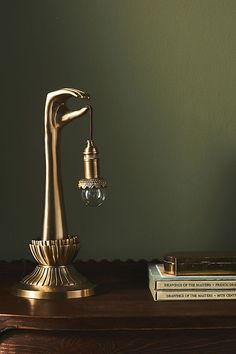 a gold faucet on top of a wooden table next to books and a lamp