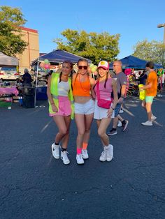 three women standing next to each other in the middle of a parking lot at an outdoor event