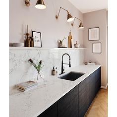 a kitchen with marble counter tops and black faucets on the wall above it