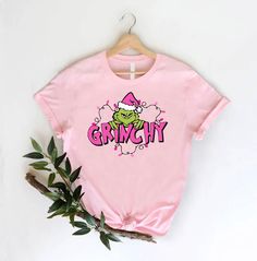 a pink t - shirt with the word grem city printed on it next to a plant