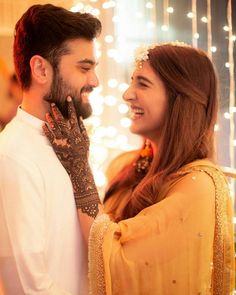 a man and woman standing next to each other with lights in the back ground behind them