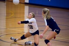 two girls playing volleyball in a gym