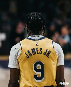 a basketball player with dreadlocks standing in front of a crowd wearing a yellow jersey