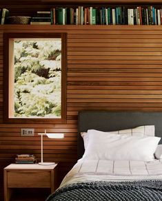 a bedroom with wood paneling and white linens on the bed, along with bookshelves