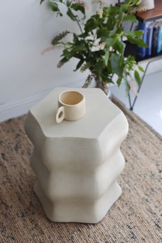 a coffee cup is sitting on top of a white vase