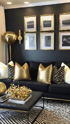 a living room filled with black couches and gold throw pillows on top of them