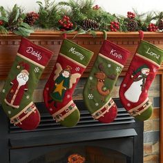 christmas stockings hanging from a fireplace mantel decorated with holly and reindeers, along with other holiday decorations