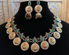 A really gorgeous jewelry set made from a mixture of pure brass (80%) and pure silver (20%). The design features small coin pine structures with Goddess Laxmi engraved on it neatly with a bright green stone on top of each coin. The earring is also same with a small jhumka added. The quality of the jewelry is top quality due to the use of authentic brass and silver. 100% guarantee on the gold and silver polish. Necklace is adjustable- loops in the back. Care Instruction: Avoid heat & substanc Small Jhumka, Boho Jewelry Gold, Goddess Laxmi, Emerald Green Stone, Pink Choker, Necklace Set Indian, Oxidized Necklace, Stone Choker, Silver Polish