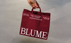 a person holding a red bag with the word blume on it