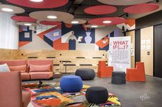 an office with colorful furniture and decorations on the walls, carpeted floors, and round lights