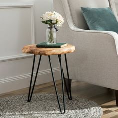 a vase with flowers sitting on top of a wooden table next to a gray chair