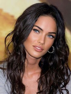 a close up of a woman with long hair and blue eyes wearing earrings on her head