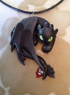 a necklace with a black dragon and green eyes on a white tablecloth covered surface