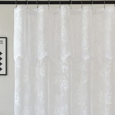 a white shower curtain hanging on the side of a wall