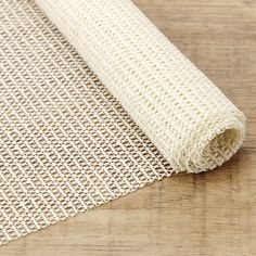 a piece of white mesh on top of a wooden table next to a roll of cloth