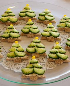 small cookies decorated with cucumber are on a glass platter