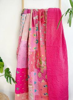 a pink blanket hanging on the wall next to a potted plant