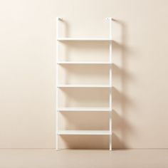 a white book shelf against a beige wall