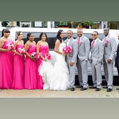 a group of people standing in front of a white car wearing pink dresses and ties