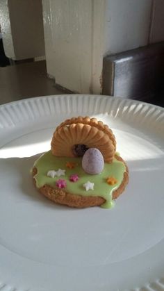 a white plate topped with a pastry covered in green icing and a bird's nest