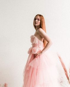 a woman in a pink dress standing next to tall grass