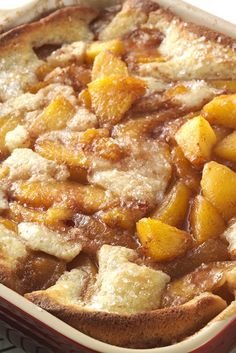 a casserole dish with peaches and powdered sugar on top, ready to be eaten