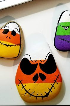 three painted rocks sitting on top of a white counter next to each other with different colored faces