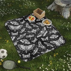 a black and white butterfly print picnic blanket sitting on top of a grass covered field