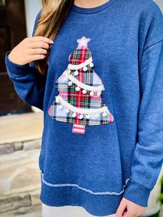 a woman wearing a blue christmas sweater with a plaid tree on the front and bottom