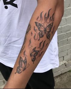 a man's arm with two butterflies on it and flames coming out of the back