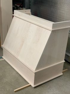 a white wooden box sitting on top of a floor next to a piece of plywood