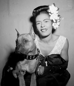 a woman sitting next to a dog with a flower in her hair on her head