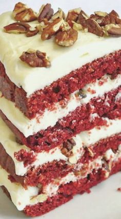 a piece of red velvet cake with white frosting and nuts