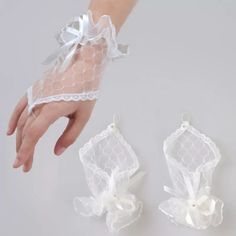 two white gloves with bows on them and one being held by someone's hand