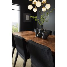 a wooden table with black chairs and vases on it