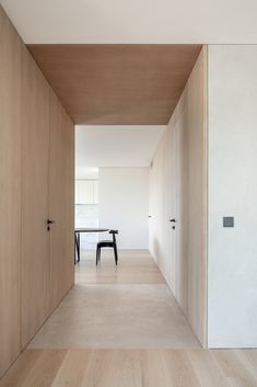 an empty hallway leading to a dining room with wooden walls and flooring on both sides