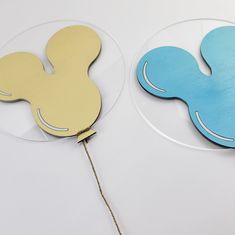 two wooden coasters with mickey mouse ears on them, one is blue and the other is yellow