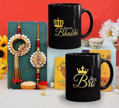 three black coffee mugs sitting on top of a table next to some flowers and other items