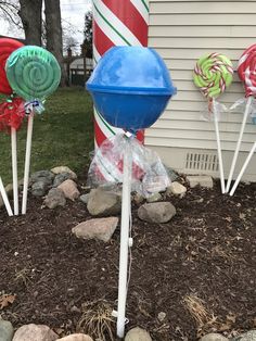 some lollipops are sitting in the dirt near a building with candy canes