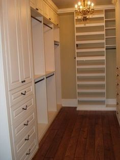 an empty walk in closet with lots of drawers and shelves on the wall, along with a chandelier hanging from the ceiling