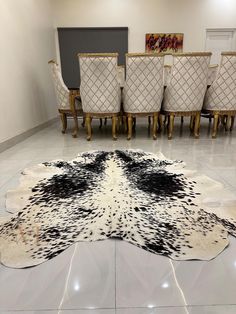 a cow hide rug in the middle of a room with chairs and tables behind it