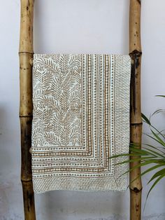 a white and brown towel hanging on a wooden chair next to a potted plant