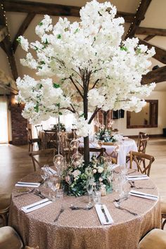 a table set up with place settings and flowers on the centerpieces for an elegant wedding reception