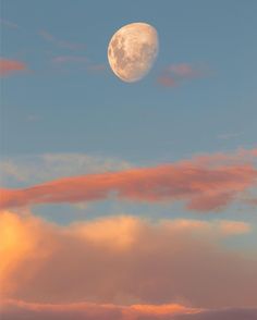 the full moon is shining brightly in the sky above some pink clouds and blue skies