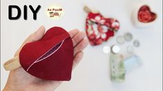 a hand holding a small red heart shaped object next to other items on a table