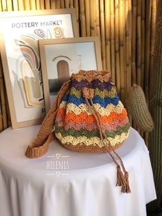 a crocheted purse sitting on top of a white table next to a cactus