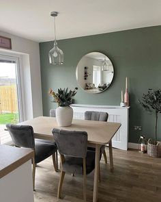 a dining room table with chairs and a mirror on the wall in front of it