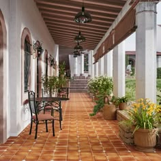 an outdoor patio with potted plants and chairs on the side walk next to it